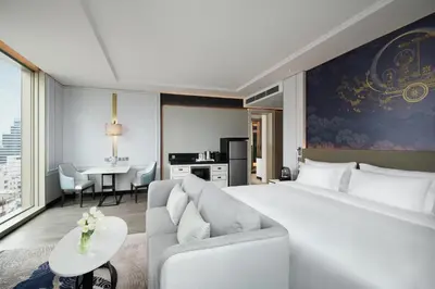 a bedroom with a bed and a couch and a table at Grande Centre Point Surawong Bangkok in Bangkok