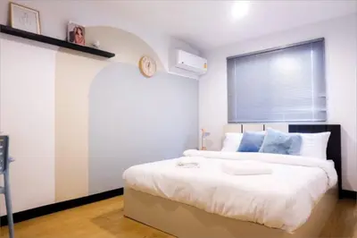 a bedroom with a large bed with a clock on the wall at Spacious 4BRTownhouse BTS Onnut 10 Sleeps with Parking in Amphoe Phra Khanong