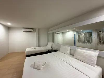 a white room with two beds and a mirror at Bed By Cruise Hotel At Samakkhi-Tivanont in Nonthaburi