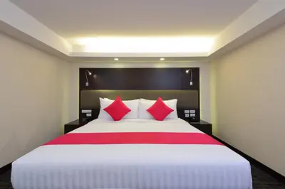 a hotel room with a large bed with red pillows at Hotel Royal Bangkok in Bangkok