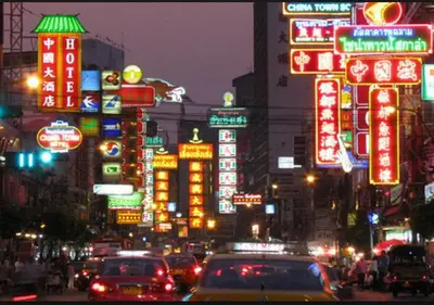 a busy city street at night with neon signs at Hotel Royal Bangkok in Bangkok