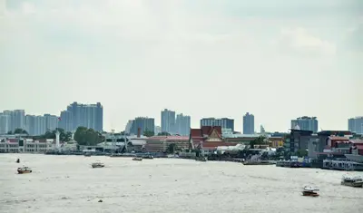 a view of a city with boats in the water at NORN Riverside Bangkok Hotel - นอนริมน้ำ in Bangkok