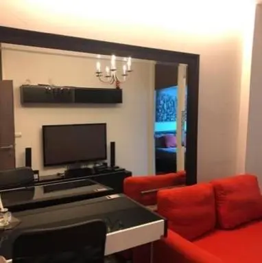 a living room with a red couch and a television at Vinn condo in Amphoe Phra Khanong