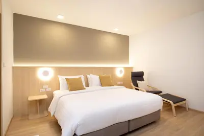 a bedroom with a large white bed and a chair at Diya Hotel Bangkok in Amphoe Phra Khanong