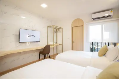 a hotel room with two beds and a tv on a wall at Diya Hotel Bangkok in Amphoe Phra Khanong