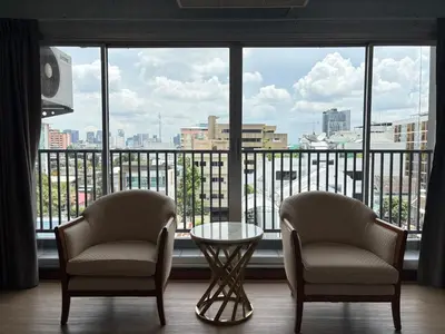two chairs and a table in front of a large window at OYO 75446 Travis Inthamara 49 in Bangkok