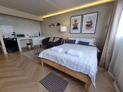 a bedroom with a large bed and a living room at Better Room ห้องพักรายวัน เมืองทองธานี C5 in Nonthaburi
