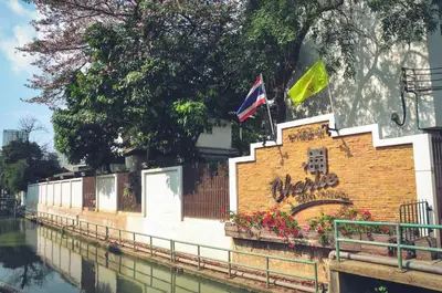 two flags on a brick wall next to a river at Charlie House Pin Klao in Bangkok