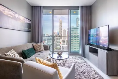 a living room with a couch and a flat screen tv at Hyde Sukhumvit 11 Branded Suites in Bangkok