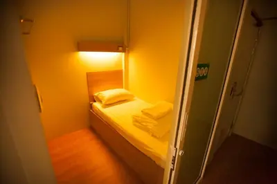 a small room with a small bed with yellow walls at Micro Hostel in Bangkok