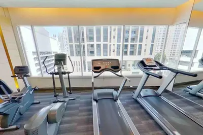 a gym with cardio machines and a large window at 2BedRoom-BestLocationBangkok-Emquartier-Metro-PhromPhong in Bangkok