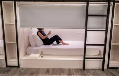a woman sitting on a bed in a bunk bed room at Comfy Crib Hostel in Bangkok