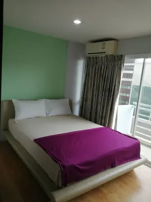 a bedroom with a bed with purple sheets and a window at BKK TEAK Hostel in Amphoe Phra Khanong