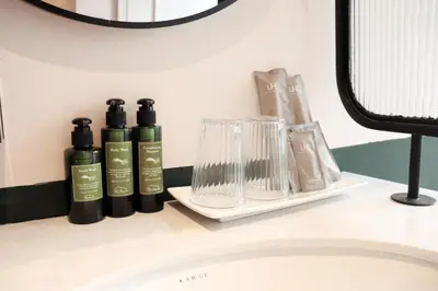a shelf with three bottles on a bathroom sink at The Quarter Ratchathewi by UHG in Bangkok
