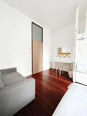 a living room with a couch and a bed at Rotinis Hostel in Pom Prap