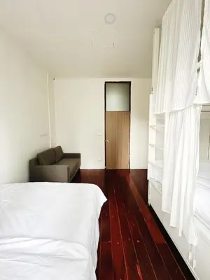 a bedroom with a white bed and a couch at Rotinis Hostel in Pom Prap