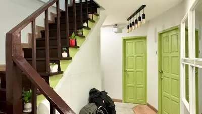 a hallway with green doors and a backpack sitting on the floor at The Tangerine Guesthouse in Bangkok