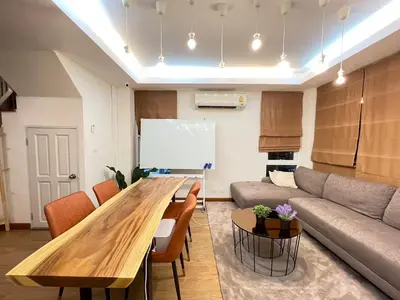 a living room with a wooden table and a couch at Modern 5-Bedroom Townhome near MRT and Local Charm in Bangkok