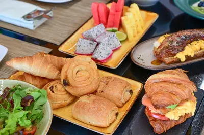 a table topped with plates of pastries and other foods at Floral Court Hotel & Residence Sukhumvit 13 in Bangkok