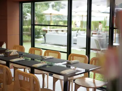 a dining room with tables and chairs and a large window at Floral Court Hotel & Residence Sukhumvit 13 in Bangkok