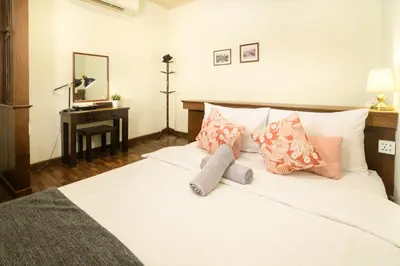 a bedroom with a white bed with pillows and a desk at Niras Bankoc Hostel in Bangkok