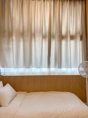 a bed in front of a window with a white curtain at La Moon House in Salaya