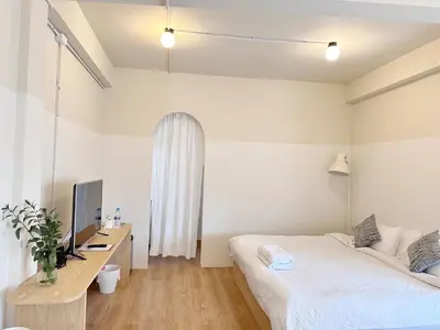 a bedroom with a bed and a desk with a television at La Moon House in Salaya