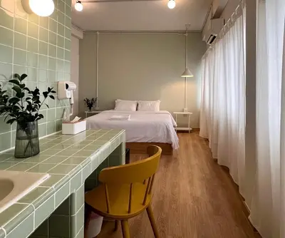 a bedroom with a bed and a desk with a chair at La Moon House in Salaya