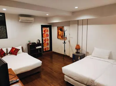 a room with two beds and a table with a lamp at mstay in Bangkok