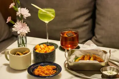 a table with a tray of food and a glass of wine at THEE Bangkok by TH District in Bangkok