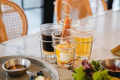 a table with four glasses of beer and a plate of food at THEE Bangkok by TH District in Bangkok