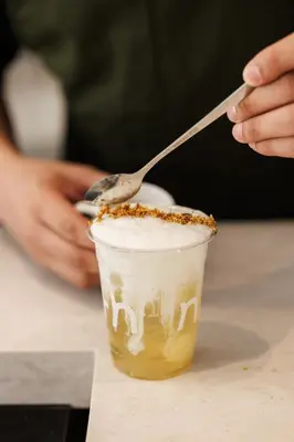 a person holding a spoon over a cup of coffee at CORRIDOR 2407 in Bangkok
