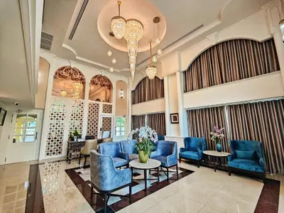a lobby with blue chairs and tables and a chandelier at Siri Ratchadamnoen Bangkok Hotel in Bangkok