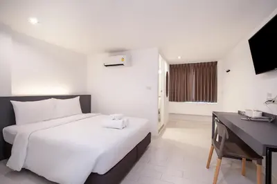 a bedroom with a large white bed and a desk at The Urban Oasis in Bangkok