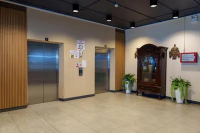 an elevator lobby with two elevators and a clock at Prom Hotel in Bangkok