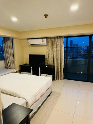 a hotel room with two beds and a large window at Affordable Serviced Apartments in Nana Omni Tower - Prime Sukhumvit location in Bangkok