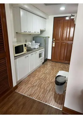 a kitchen with white cabinets and a wooden floor at Affordable Serviced Apartments in Nana Omni Tower - Prime Sukhumvit location in Bangkok