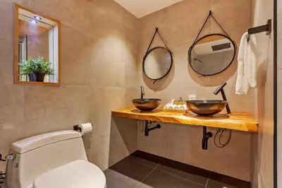 a bathroom with a toilet and two mirrors on the wall at Chic loft in Bangkok