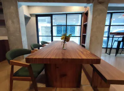 a wooden table with chairs and a vase of flowers on it at N5 Ratchawong Hostel in Bangkok