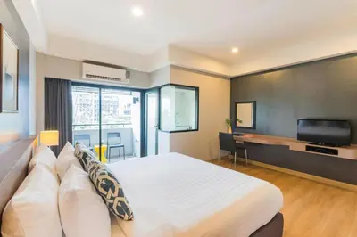 a bedroom with a large bed and a flat screen tv at Alt Hotel Nana by UHG in Bangkok