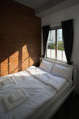 a bed in a bedroom with a brick wall at G5 Hostel in Bangkok