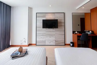 a bedroom with a bed with a tv on a wall at Frame Hotel Bangkok in Bangkok