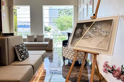 a living room with a painting on a stand at Frame Hotel Bangkok in Bangkok