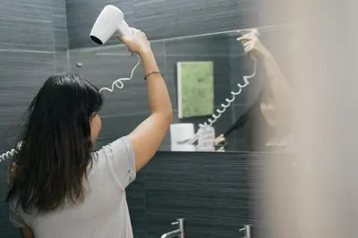a woman blow drying her hair in front of a mirror at Qilombo Hostel Silom in Bangkok