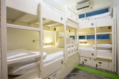 a room with three bunk beds with white bunkresses at Qilombo Hostel Silom in Bangkok