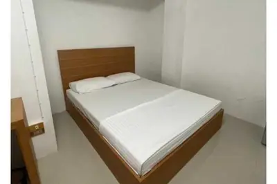 a small bedroom with a bed with white sheets at OYO 75577 Palace Hostel in Amphoe Phra Khanong