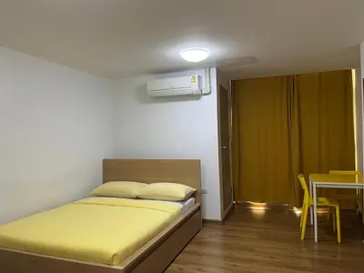 a bedroom with a bed and a table with a yellow chair at Dao Jaras Fah Hometel ดาวจรัสฟ้าโฮมเทล in Bangkok