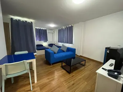a living room with a blue couch and a tv at Dao Jaras Fah Hometel ดาวจรัสฟ้าโฮมเทล in Bangkok