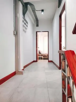 a hallway with white walls and a room with a table at Jira19Hostel in Bangkok