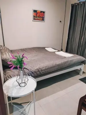a room with a bed and a table with a vase with flowers at Jira19Hostel in Bangkok